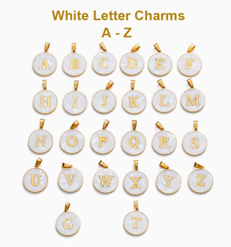 Puede incluir: Una colecci&oacute;n de dijes redondos blancos con letras doradas del alfabeto de la A a la Z. Cada colgante circular tiene una superficie blanca lisa con un borde dorado y una peque&ntilde;a argolla en la parte superior para joyer&iacute;a.