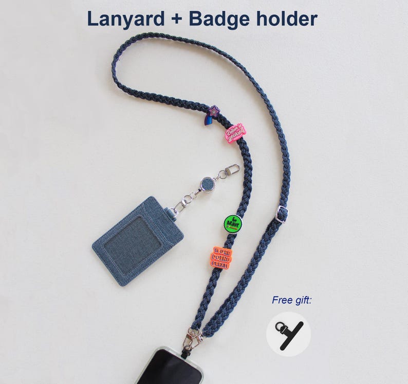 May include: A dark blue braided lanyard with a matching denim-textured badge holder. The lanyard features several small colorful charms and a retractable reel. Text at the top reads Lanyard + Badge holder and Free gift.