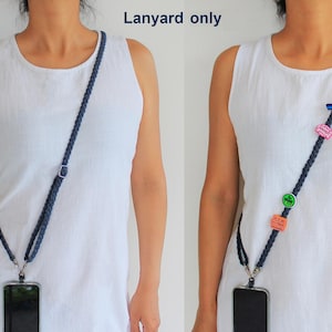 May include: A dark blue braided crossbody lanyard with a silver-toned metal adjuster and two swivel clips attached to a smartphone. The right view shows the same lanyard decorated with four small colorful charms in various shapes.