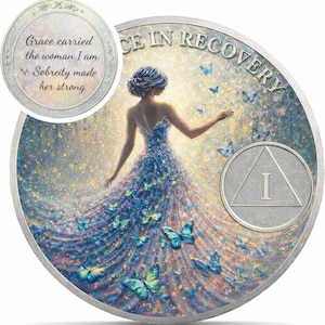 May include: A silver coin with a woman in a blue dress surrounded by butterflies. The coin has the words "Grace carried the woman I am. Sobriety made her strong." and "CE IN RECOVERY". An "I" is also visible.