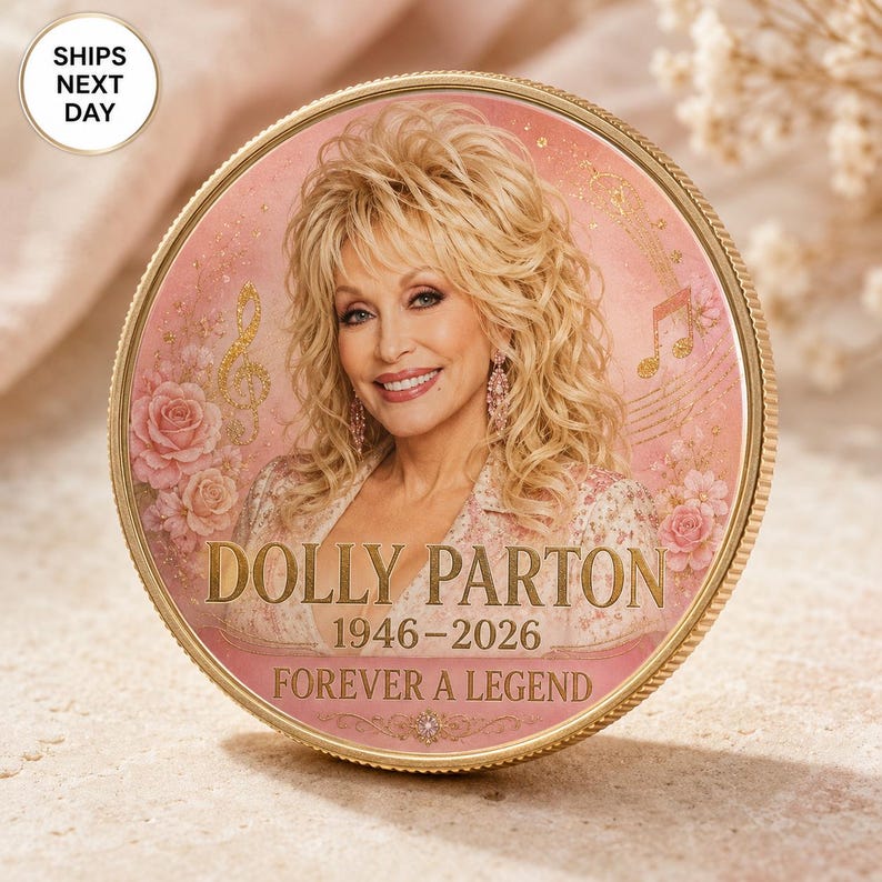 K&ouml;nnte beinhalten: Eine kreisf&ouml;rmige Gedenkm&uuml;nze mit einem Portr&auml;t von Dolly Parton mit blondem Haar, umgeben von rosa Rosen und goldenen Musiknoten. Der Text lautet DOLLY PARTON, 1946-2026 und FOREVER A LEGEND in goldener Schrift auf einem zartrosa Hintergrund.