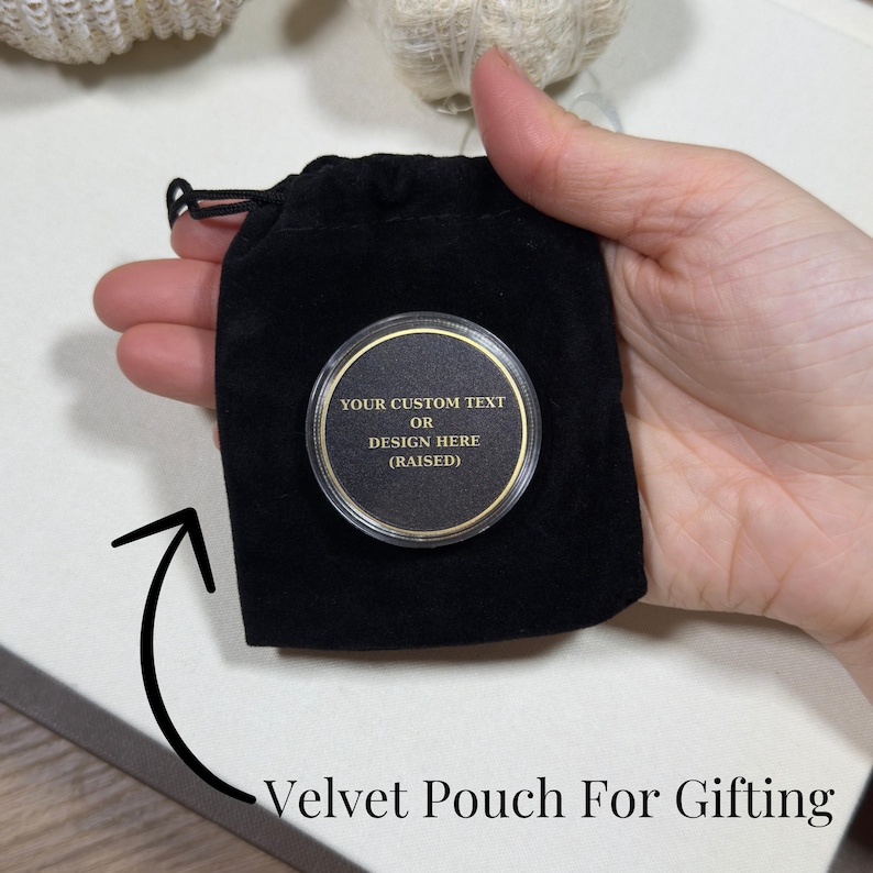 Pode incluir: Uma bolsa de veludo preta com fecho de cord&atilde;o, contendo um item redondo com c&uacute;pula transparente e borda dourada. O item tem um centro preto com texto dourado: "YOUR CUSTOM TEXT OR DESIGN HERE (RAISED)".