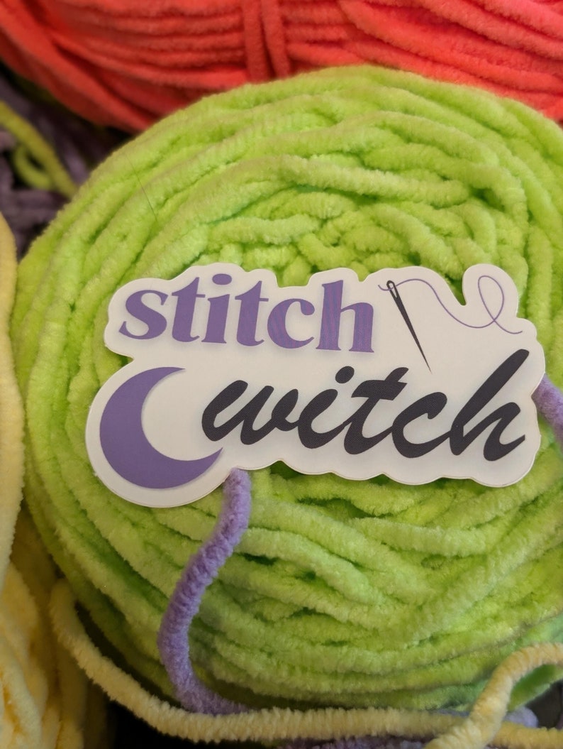 May include: A lime green ball of yarn with a sticker that says "stitch witch" featuring a crescent moon and a needle and thread design.