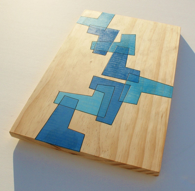 May include: A wooden cutting board with a blue geometric design. The design is made up of various shapes and sizes of blue squares and rectangles.
