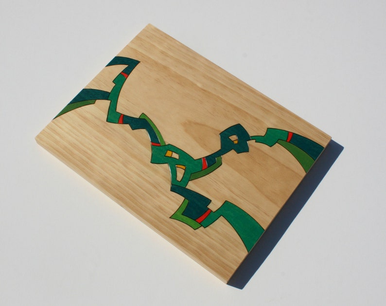 Puede incluir: Una pieza de arte de pared de madera con un dise&ntilde;o abstracto en verde, rojo y amarillo.