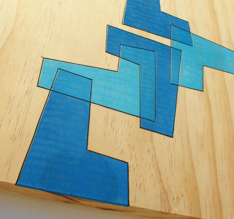 May include: Abstract geometric design painted on a light wood surface. The design is made up of overlapping blue shapes.
