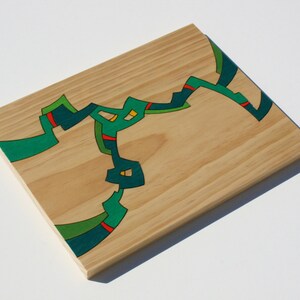 Puede incluir: Una tabla de madera con un dise&ntilde;o abstracto pintado en verde, azul y amarillo.