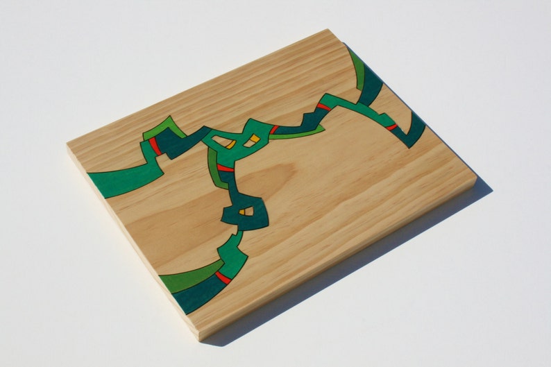 Puede incluir: Una tabla de madera con un dise&ntilde;o abstracto pintado en verde, azul y amarillo.