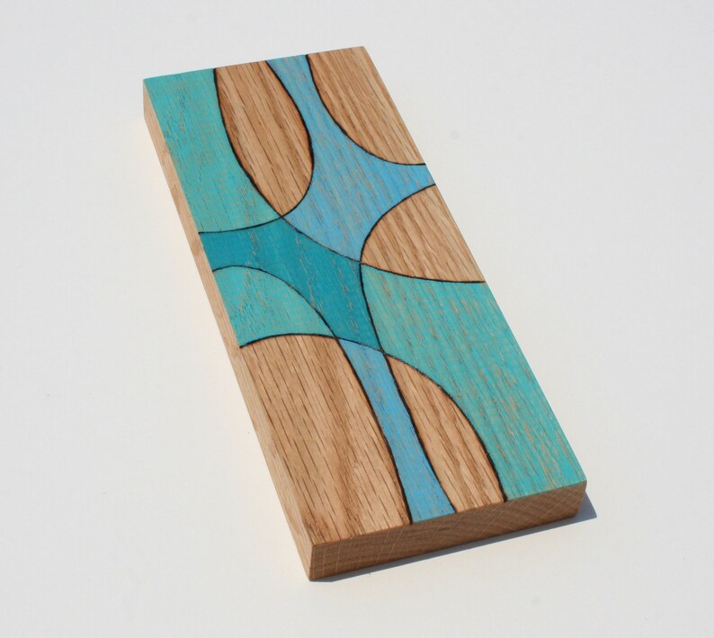 May include: A wooden wall art piece with a geometric design in shades of blue and teal. The wood has a natural grain pattern.