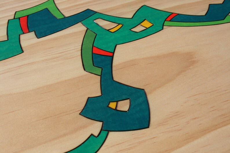 Puede incluir: Dise&ntilde;o abstracto sobre una superficie de madera. El dise&ntilde;o est&aacute; formado por formas de color turquesa, verde, amarillo y rojo.
