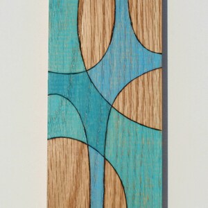 May include: A wooden wall art piece with a geometric design. The design features a series of overlapping circles and curves in shades of blue and brown.