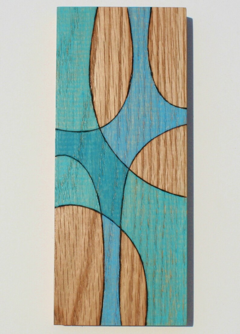 May include: A wooden wall art piece with a geometric design. The design features a series of overlapping circles and curves in shades of blue and brown.