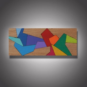 May include: Abstract geometric art piece with colorful shapes on a wood background. The shapes are in shades of blue, green, red, orange, yellow, and purple.