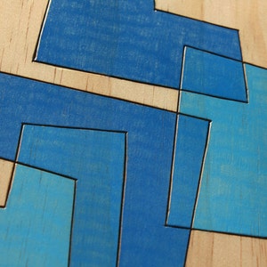 May include: Abstract geometric design painted on a wooden surface. The design features overlapping shapes in shades of blue.
