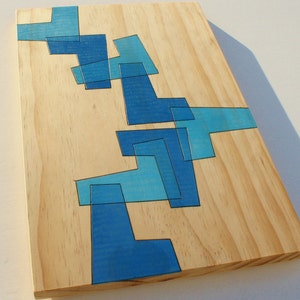 May include: A wooden board with a blue abstract design painted on it. The design is made up of geometric shapes and lines.
