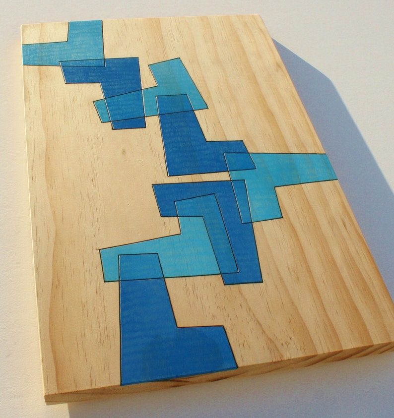 May include: A wooden board with a blue abstract design painted on it. The design is made up of geometric shapes and lines.