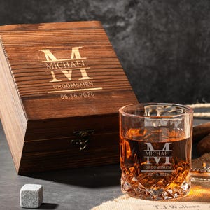 Könnte beinhalten: Eine Holzkiste und ein Whiskeyglas mit Rautenmuster. Die Kiste und das Glas sind mit dem Namen "MICHAEL", dem Wort "GROOMSMEN" und dem Datum "06.16.2026" graviert. Das Glas ist mit bernsteinfarbener Flüssigkeit gefüllt.