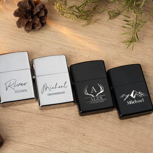 May include: Four personalized lighters, two silver and two black, with custom engravings. The silver lighters have names and titles, while the black ones feature a deer antler design and mountain graphic. A stylish gift.
