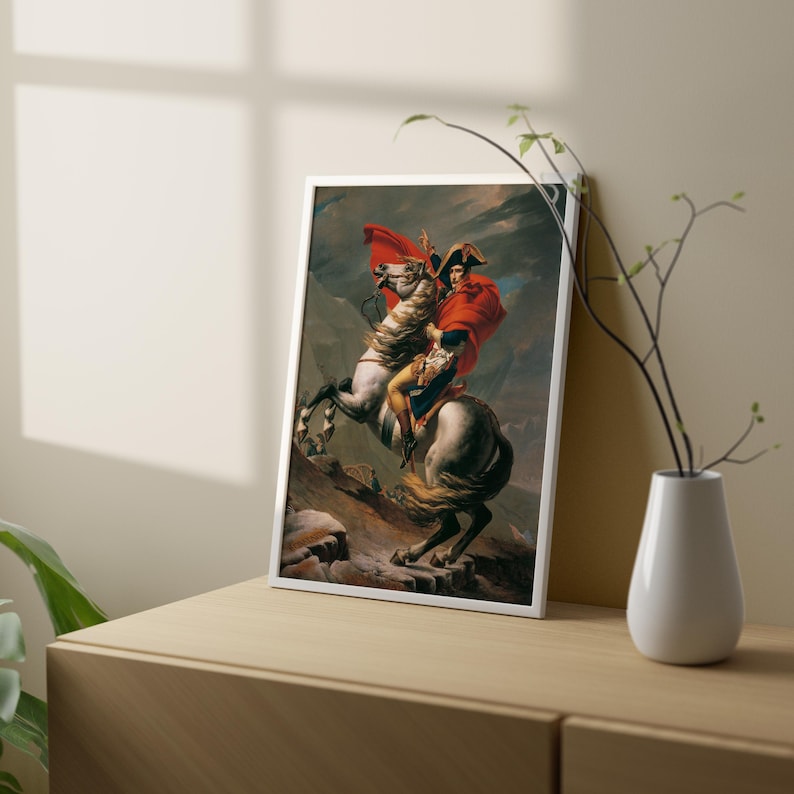 May include: A framed painting of a man on horseback, riding through a mountainous landscape. The man is wearing a red cloak and a white hat. The horse is white with a brown saddle. The painting is set against a backdrop of a stormy sky.