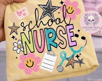 Pode incluir: Uma t-shirt amarelo-pálido com uma impressão gráfica com o texto school NURSE em letras coloridas. O design inclui um estetoscópio, uma prancheta, estrelas, flores com rostos sorridentes e um penso com corações. Um logótipo circular diz CAFFEINE SKULL BOUTIQUE.