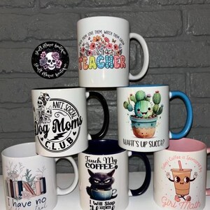 May include: A collection of 7 ceramic mugs with various designs and text. The mugs are white with black, blue, pink, and green accents. The text on the mugs includes "Teacher", "Anti Social Dog Moms Club", "What's Up Succa?", "Touch My Coffee", "I Will Slap You So Hard", "I Have No Shelf Control", and "Today's Coffee Is Sponsored By Girl Math".