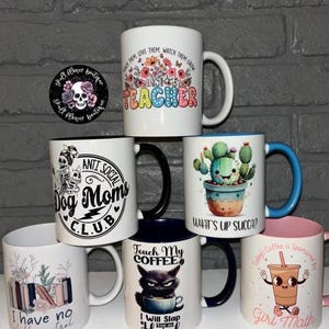 May include: A collection of 7 ceramic mugs with various designs and text. The mugs are white with black, blue, pink, and green accents. The text on the mugs includes "Teacher", "Anti Social Dog Moms Club", "What's Up Succa?", "Touch My Coffee", "I Will Slap You So Hard", "I Have No Shelf Control", and "Today's Coffee Is Sponsored By Girl Math".