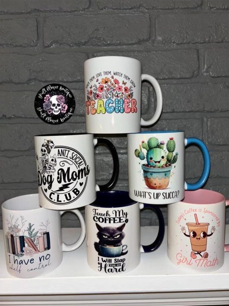 May include: A collection of 7 ceramic mugs with various designs and text. The mugs are white with black, blue, pink, and green accents. The text on the mugs includes "Teacher", "Anti Social Dog Moms Club", "What's Up Succa?", "Touch My Coffee", "I Will Slap You So Hard", "I Have No Shelf Control", and "Today's Coffee Is Sponsored By Girl Math".