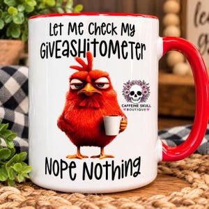 May include: A white ceramic mug with a red handle and rim. The mug features a graphic of a grumpy red chicken holding a small white cup. Text reads: Let Me Check My GiVEASHITOMETER, and below the chicken: NOPE Nothing. A small skull logo is present.