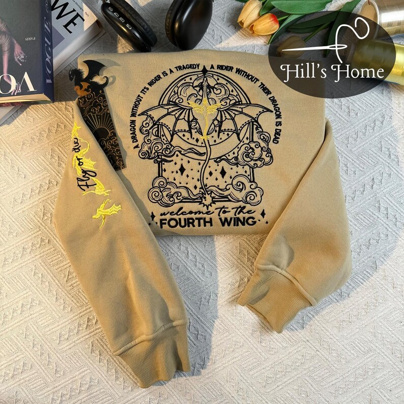 May include: A beige sweatshirt with a black embroidered design of a dragon with the text "A dragon without its rider is a tragedy. A rider without their dragon is dead. Welcome to the Fourth Wing."
