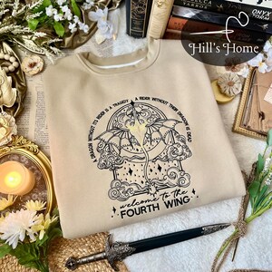 May include: A beige sweatshirt with a black graphic of a dragon and the text "A dragon without its rider is a tragedy. A rider without their dragon is dead. Welcome to the Fourth Wing."