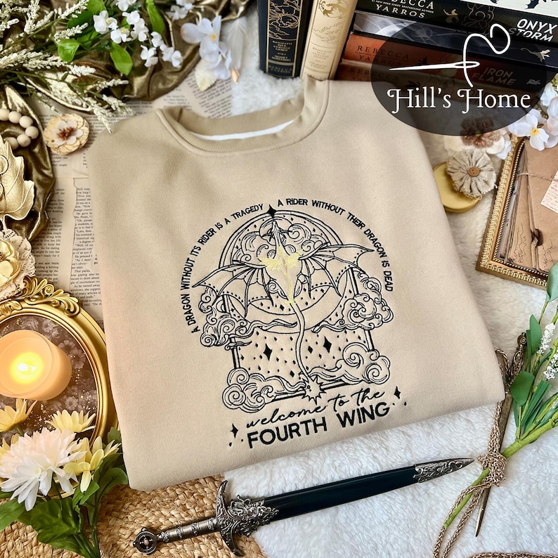 May include: A beige sweatshirt with a black graphic of a dragon and the text "A dragon without its rider is a tragedy. A rider without their dragon is dead. Welcome to the Fourth Wing."