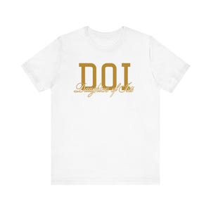 Peut inclure: T-shirt blanc avec un motif doré qui dit "DOI Daughters of Isis"