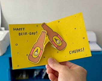 Biglietto pop-up "Buona giornata della birra", illustrazione di una birra, cartoncino spesso (10 cm x 11,5 cm)