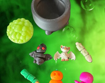 Figuras articuladas de Halloween impresas en 3D: caldero, bruja, murciélago, lanza, calabaza y dedos.