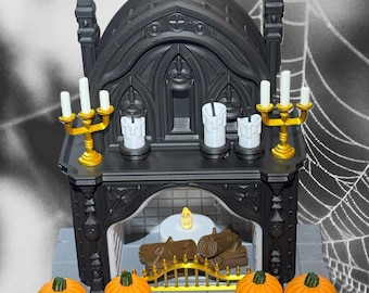 Puede incluir: Una chimenea negra en miniatura con candelabros dorados, velas blancas y calabazas naranjas. La chimenea tiene un diseño gótico con una base gris y una vela brillante en el interior. Un artículo decorativo con temática de Halloween o otoño.