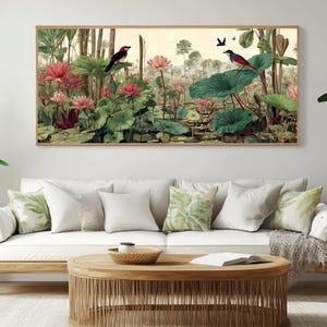 May include: A framed botanical print featuring a serene pond scene with pink lotus flowers, lush green lily pads, and two birds perched on the foliage. The artwork is set against a neutral background and framed in a light wood.