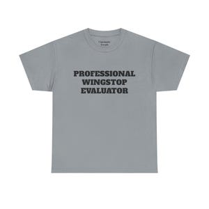 May include: A light gray t-shirt with the text "PROFESSIONAL WINGSTOP EVALUATOR" printed in black.