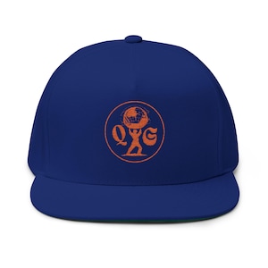 May include: A royal blue snapback cap featuring a circular orange graphic on the front panel. The design depicts a figure holding up a globe, flanked by the letters Q and G, all enclosed within a thin orange circle with a distressed texture.