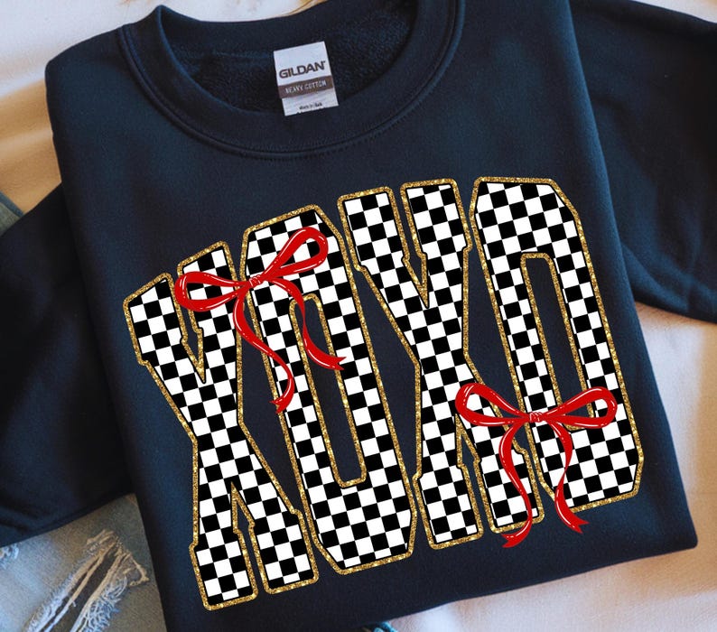 Puede incluir: Sudadera negra con la palabra "XOXO" en un patr&oacute;n de cuadros blanco y negro, con ribete de purpurina dorada y lazos rojos. Una prenda informal.