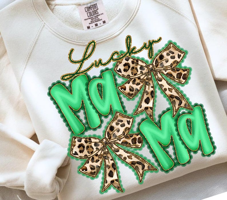 May include: Cream-colored sweatshirt with the words "Lucky Mama" in gold script. The word "Mama" is in large, green, bubble letters with a scalloped border. Two leopard print bows are also featured.