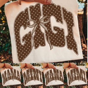 Könnte beinhalten: Ein weißes T-Shirt mit dem Wort GIGI in großen, braunen, gepunkteten Buchstaben, verziert mit einer dekorativen braunen Schleife in der Mitte. Das Design wiederholt sich in kleineren Varianten unten mit den Wörtern MAMA, NANA und MIMI.