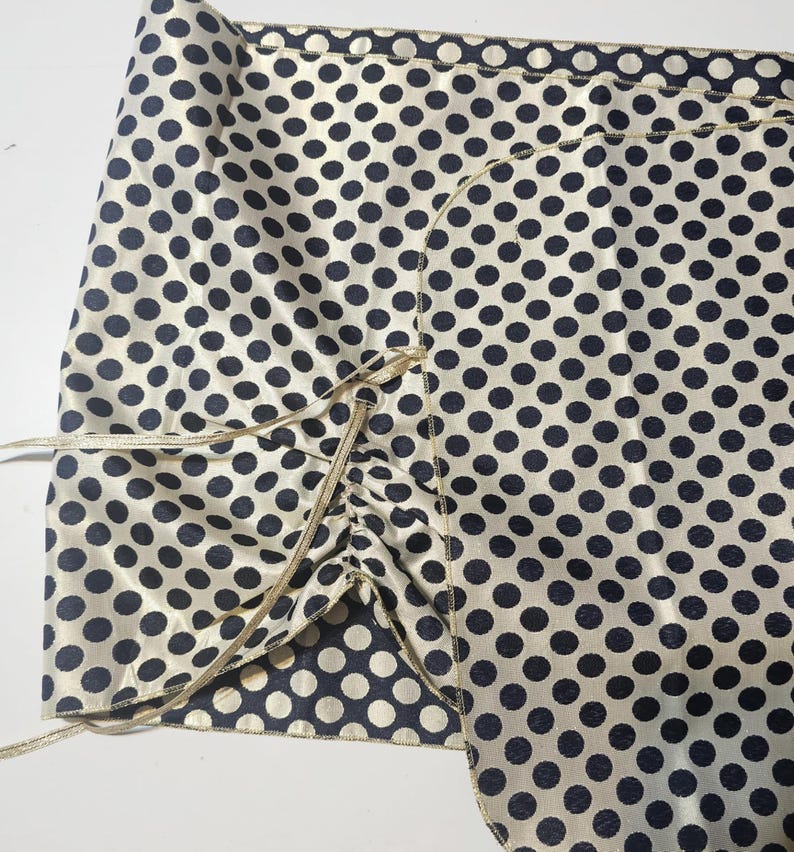 Navy and gold polka dot evening wrap laid flat showing its reversible construction and ribbon ties