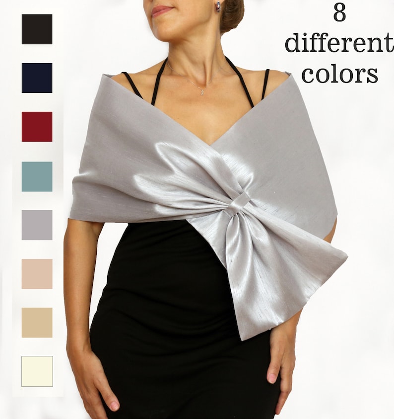 "Elegant satin evening shawl in metallic gray featuring a large decorative bow at the front. Available in 8 colors, this stylish wrap is ideal for formal events, weddings, or as a mother-of-the-bride accessory. Adds a chic touch to any outfit.