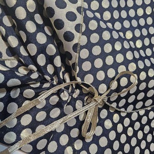 Satin ribbon fastening detail on the reversible navy and gold polka dot formal shoulder wrap