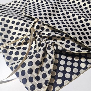 Reversible polka dot taffeta shawl laid flat showing the gold side and satin ribbon fastening