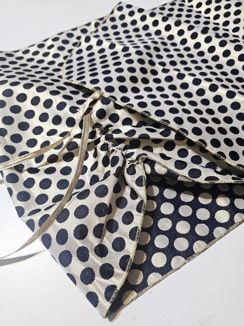 Reversible polka dot taffeta shawl laid flat showing the gold side and satin ribbon fastening