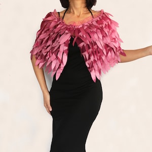 May include: A pink feather shawl with a delicate, layered design. The shawl is made of soft, flowing fabric and has a romantic, ethereal feel.