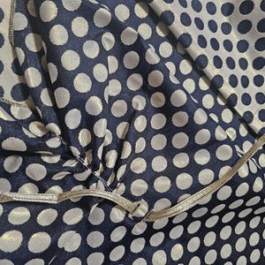 Close-up of navy polka dot taffeta and satin ribbon tie used to secure the shawl