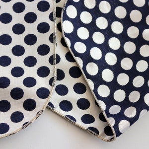 Close-up of reversible taffeta fabric showing navy with gold dots and gold with navy dots