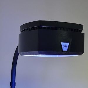May include: A black, adjustable, desk lamp with a blue light. The lamp has a rectangular head with a small logo on the front.